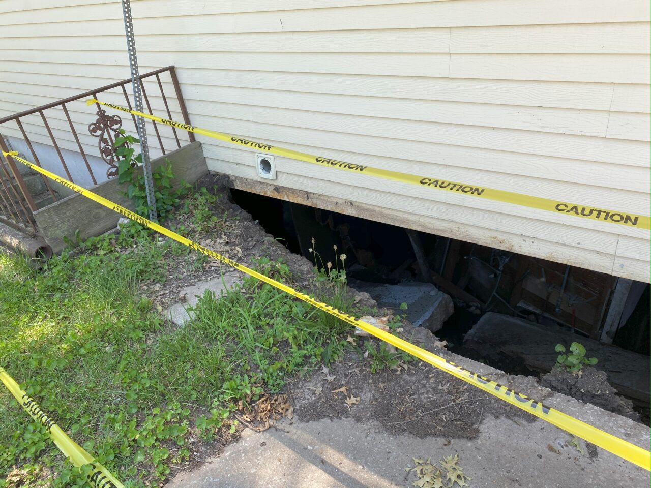 a house with a massive foundation gap between the wall and the main pavement.